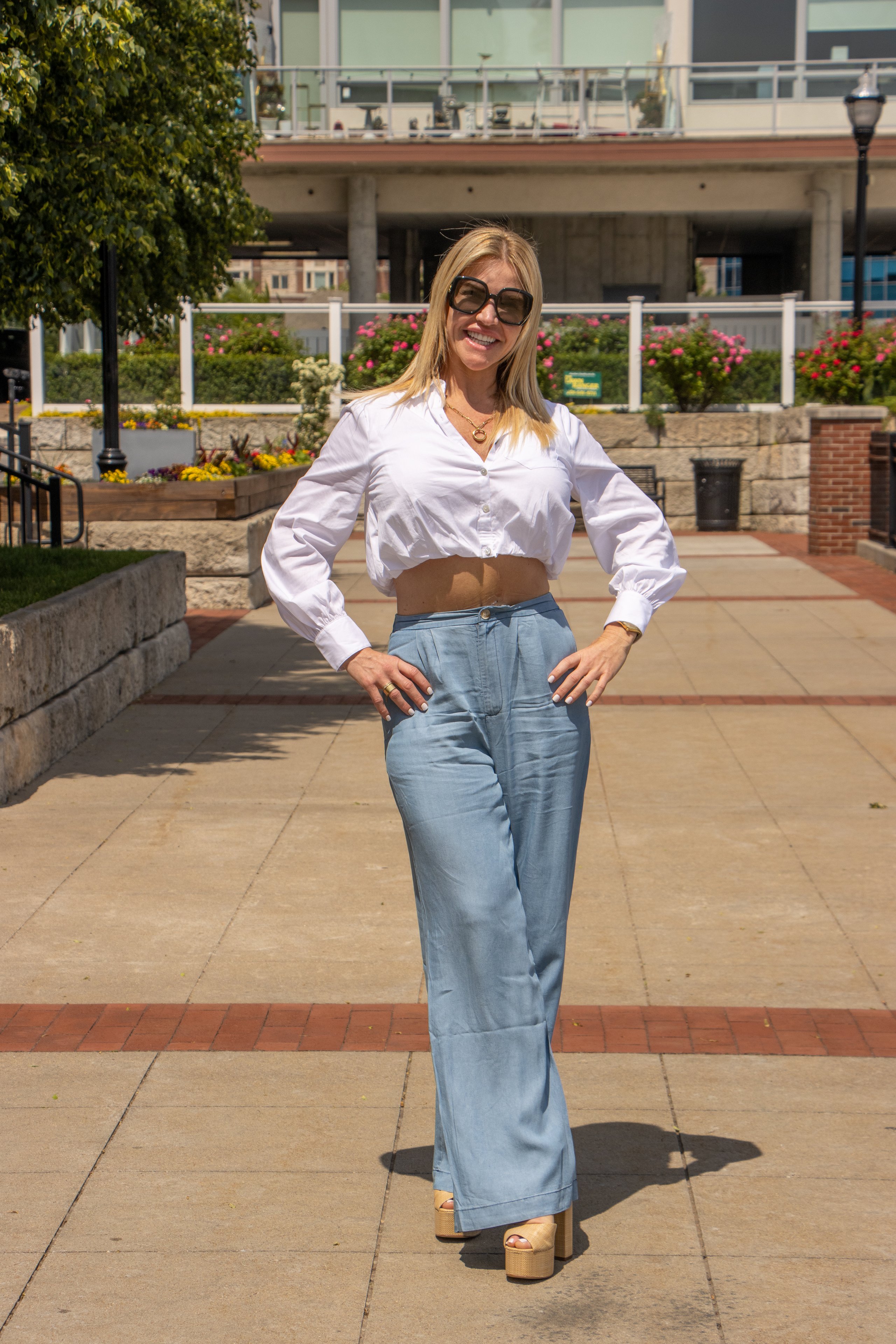 Fiona Rooney in a white shirt and jeans on a sunlit plaza