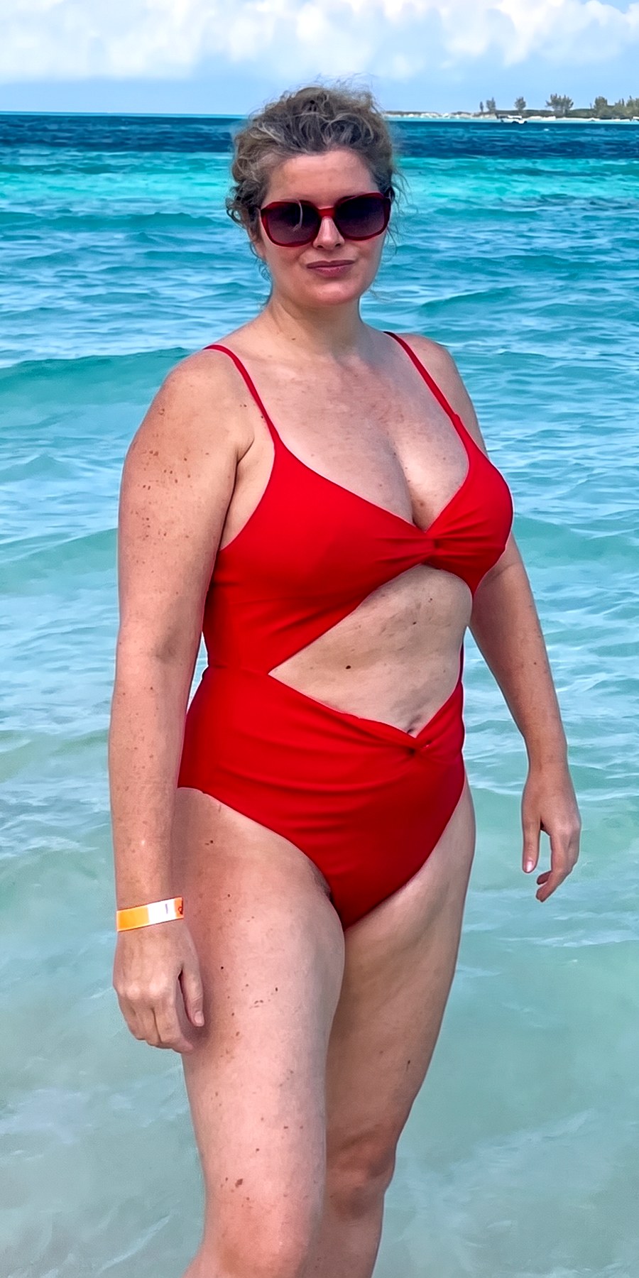 Before, standing in the sea in a red swimsuit